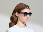 Model is wearing The GRUNYA SUN in size 47 in Black with Denim Blue Tinted Lenses