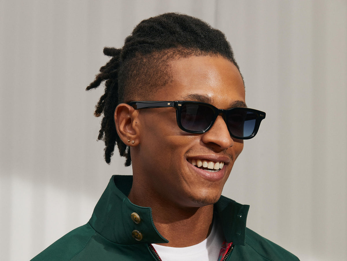Model is wearing The KLUTZ SUN in Black in size 50 with Denim Blue Tinted Lenses