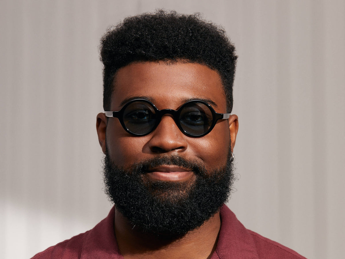 Model is wearing The ZOLMAN SUN in Black in size 42 with Blue Glass Lenses